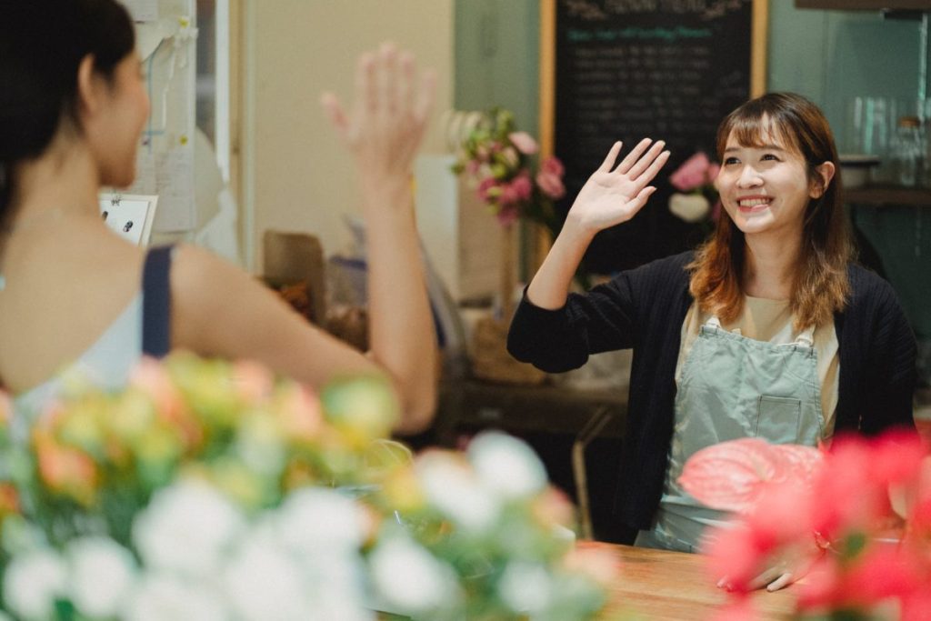 happy female florist waving hand in shop
